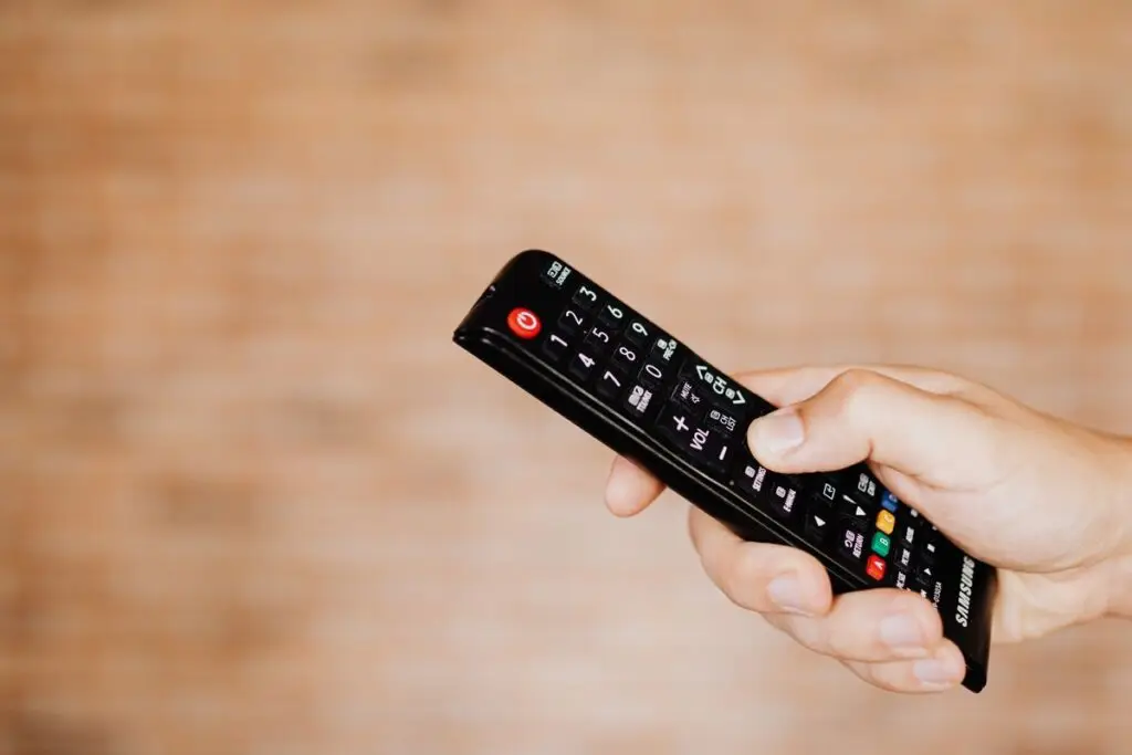 Mão segurando um controle remoto de TV