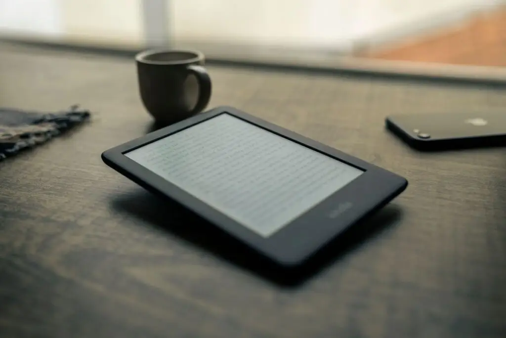 Leitor de e-book e xĂcara sobre uma mesa de madeira
