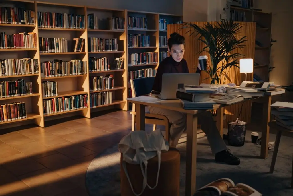 Mulher estudando à noite com livros, laptop e café
