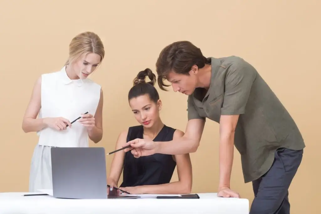 Grupo de profissionais conversando em torno de um laptop