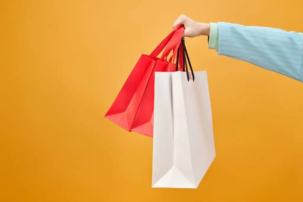 Mão segurando várias sacolas de compras coloridas
