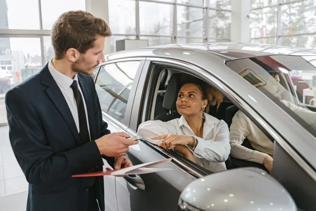 Vendedor entregando as chaves de um carro a uma cliente na concessionária