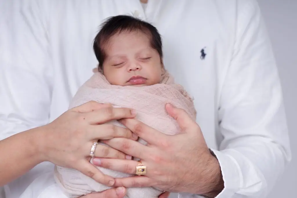 Pais segurando o bebê recém-nascido dormindo