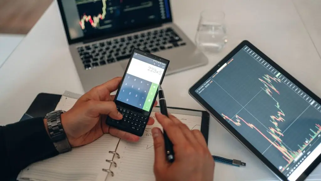 Mesa de trabalho com gráficos, dispositivos e calculadora para análise de investimentos
