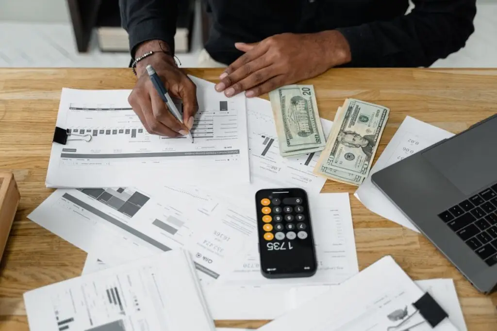 Homem organizando as finanças com calculadora e laptop