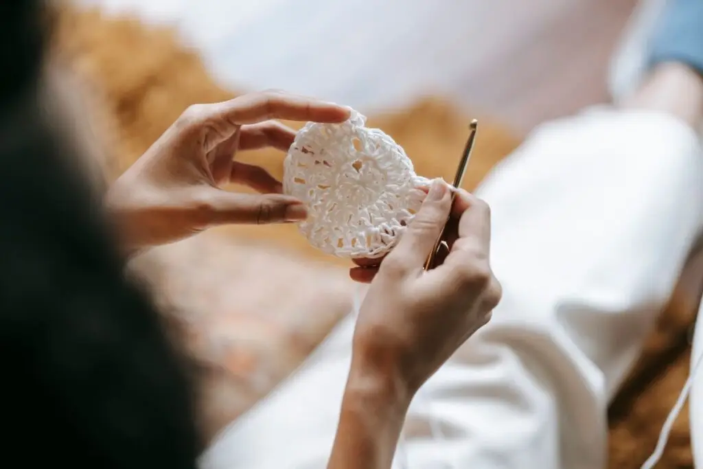 Mãos fazendo crochê com linha em casa